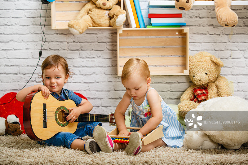 蹒跚学步的双胞胎在家里一起玩图片素材