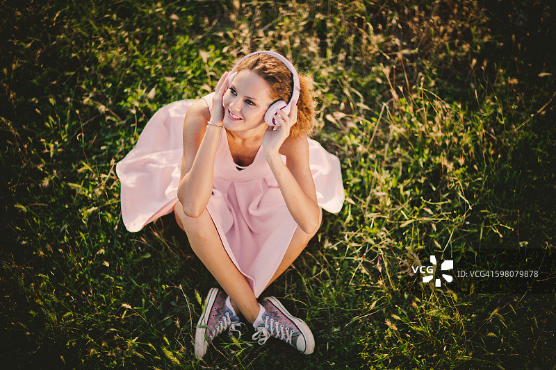 坐在草地上戴耳机的女孩图片素材
