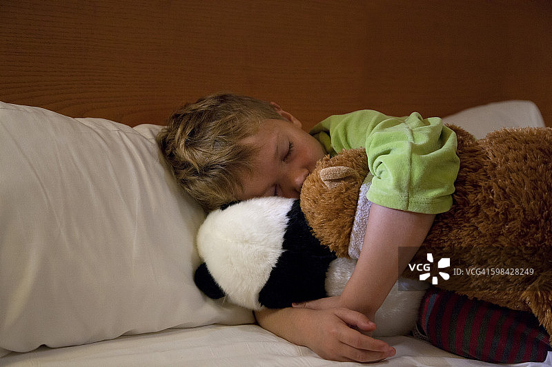 和泰迪熊一起睡觉的孩子图片素材
