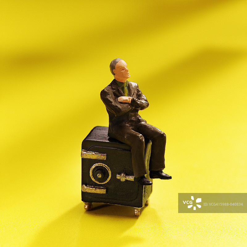 坐在保险箱上的小雕像图片素材