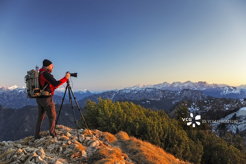 在阿尔卑斯山携带三脚架和背包的自然摄影师图片素材