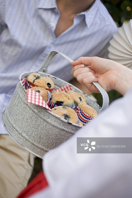 手拿蓝莓松饼罐头，背景是男人图片素材