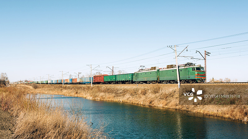 沿着池塘行驶的货运列车，水中倒影图片素材