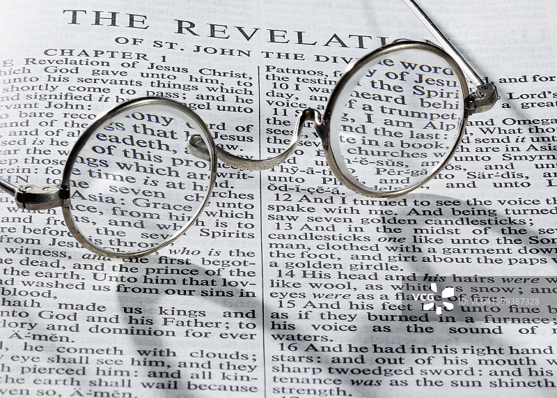 《启示录》书页上的老式圆形老花镜图片素材