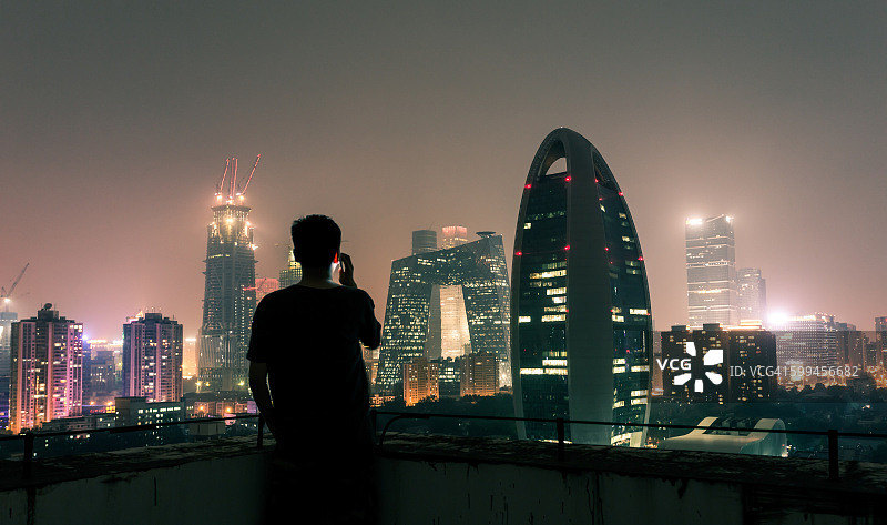 坐在屋顶上使用智能手机的年轻男人图片素材