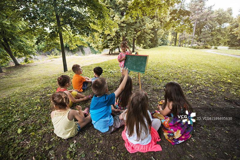 在自然环境中教育朋友们的小女孩图片素材