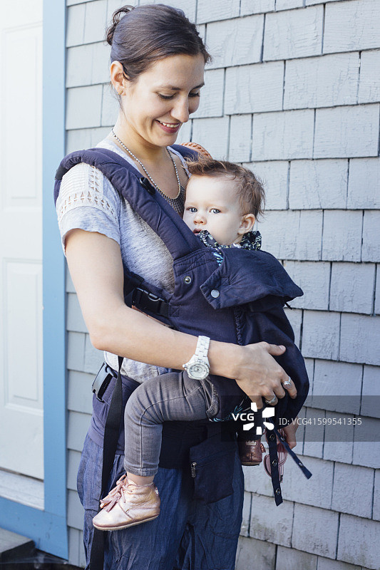年轻女子用吊带在前廊抱着女儿图片素材