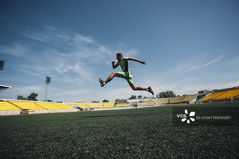 在训练期间在体育场跑步的运动型年轻男子全身照图片素材