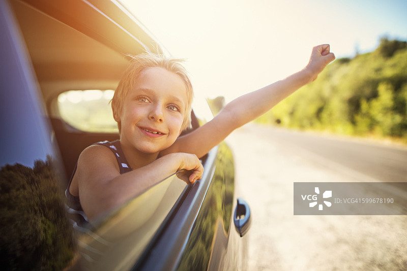 在公路旅行中，小男孩从车里向外看图片素材