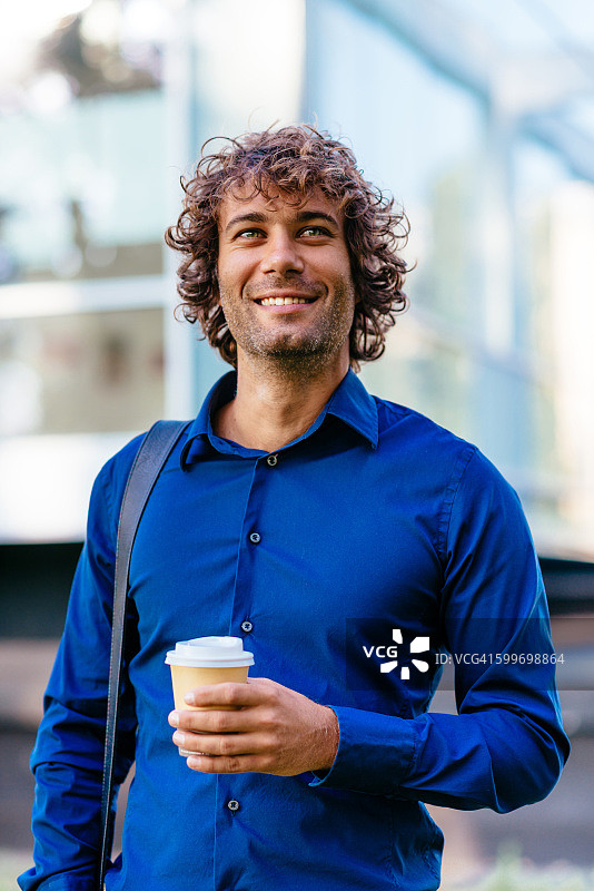 手持咖啡杯的年轻英俊男子肖像图片素材