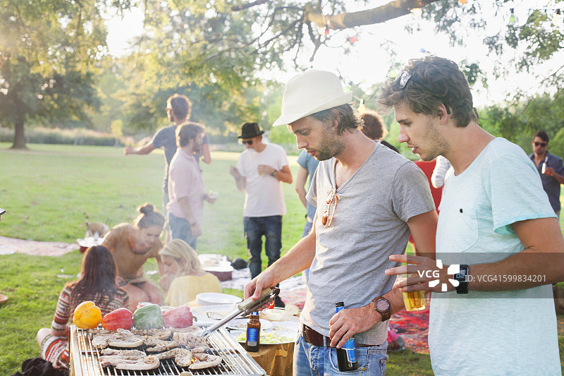 年轻男人在公园的聚会上烧烤图片素材