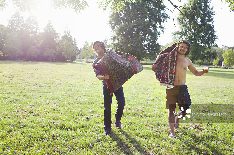 两位年轻人携带毛毯参加日落公园派对图片素材