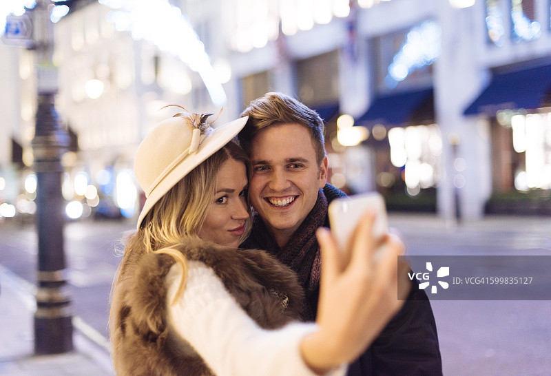 年轻情侣在英国伦敦新邦德街圣诞节用手机自拍图片素材