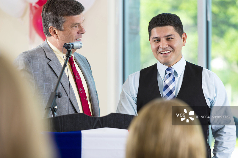 年长的政治家在讲台上介绍西班牙裔男子图片素材