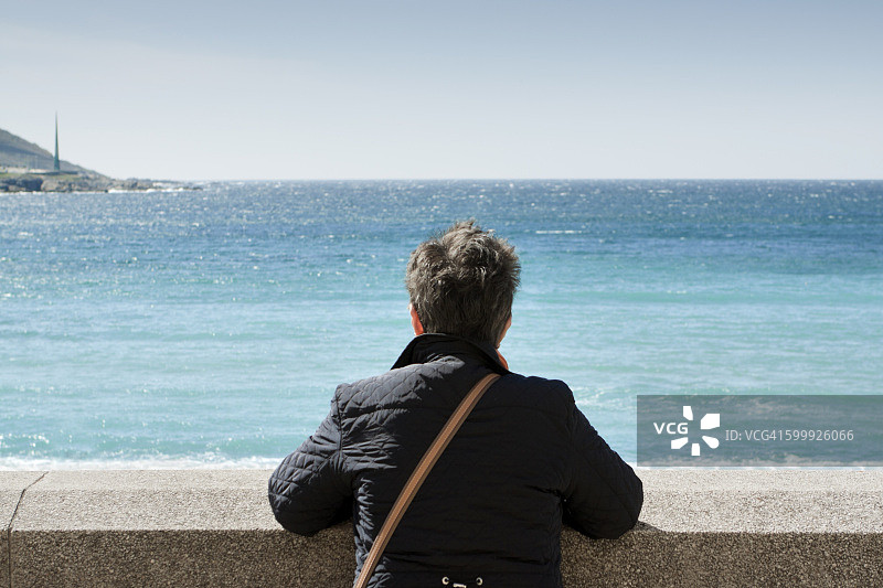 中年妇女在西班牙加利西亚的拉科鲁尼亚看着大西洋图片素材