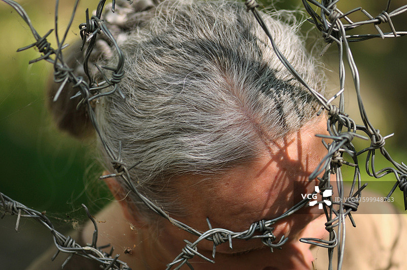 带刺铁丝网中的女人头部图片素材