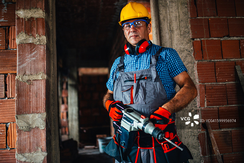拿着钻头的男建筑工人图片素材