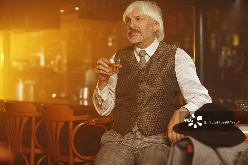 浪漫复古风老年男人在旧酒吧喝威士忌图片素材