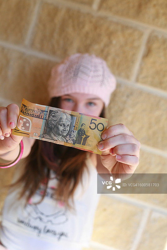 戴着粉色帽子的少女拿着澳大利亚钱币图片素材