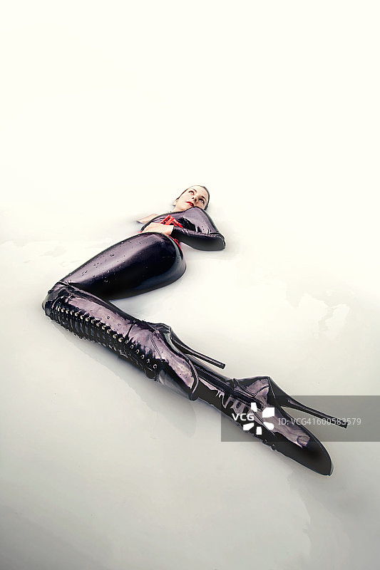 身穿乳胶服装躺在牛奶浴中的女人图片素材