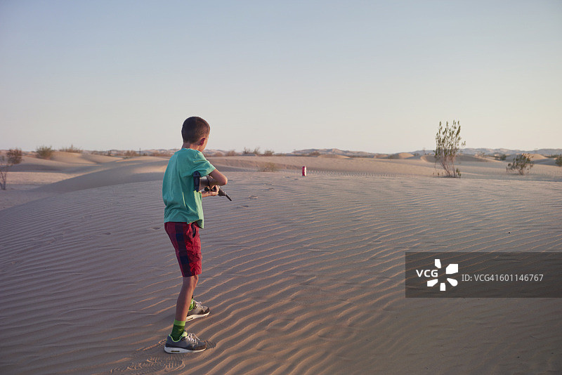 男孩在沙漠中射击BB枪图片素材