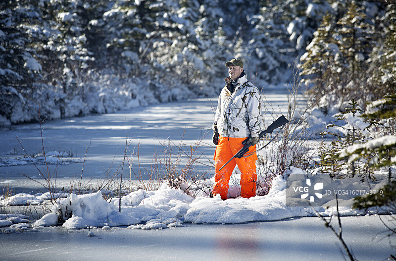 在结冰湖边穿亮色裤子的猎人图片素材