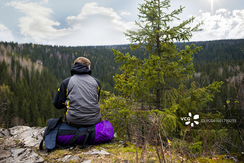 坐在偏远山顶上的白人徒步旅行者图片素材