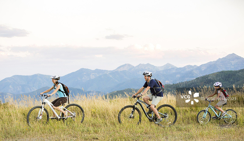 白人家庭在田野里骑山地自行车图片素材
