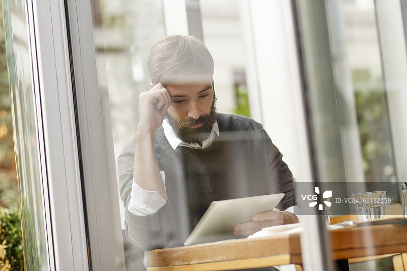在餐厅看平板电脑的年轻男人图片素材