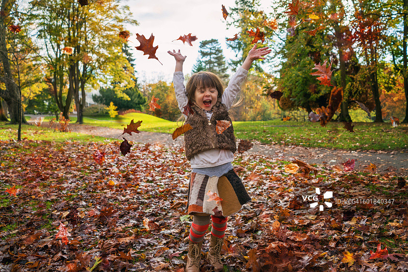 女孩在空中抛洒秋叶图片素材