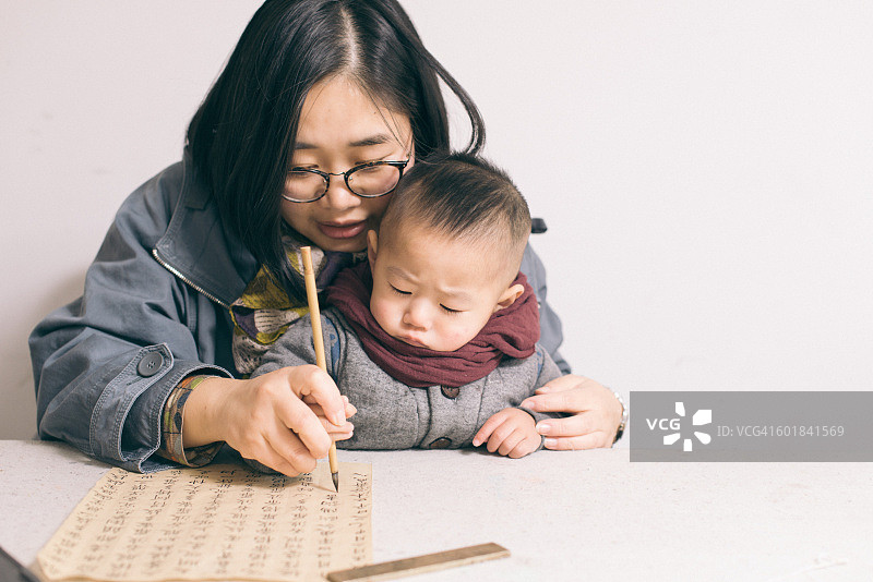 母亲和儿子练习中国书法图片素材