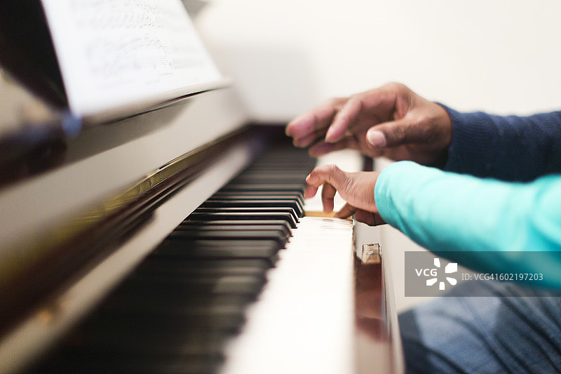 在南非开普敦，女孩（6-7岁）和祖父一起弹钢琴图片素材