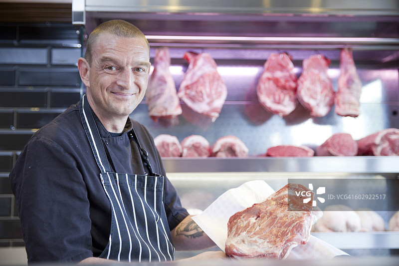 肉店师傅手持新鲜肉的肖像图片素材
