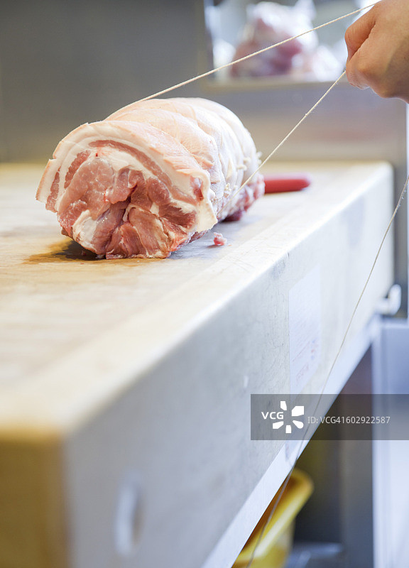 肉店里屠夫双手捆扎肉块的特写图片素材