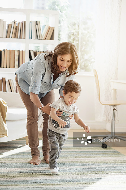 母亲抱着正在学步的儿子（2-3岁）图片素材