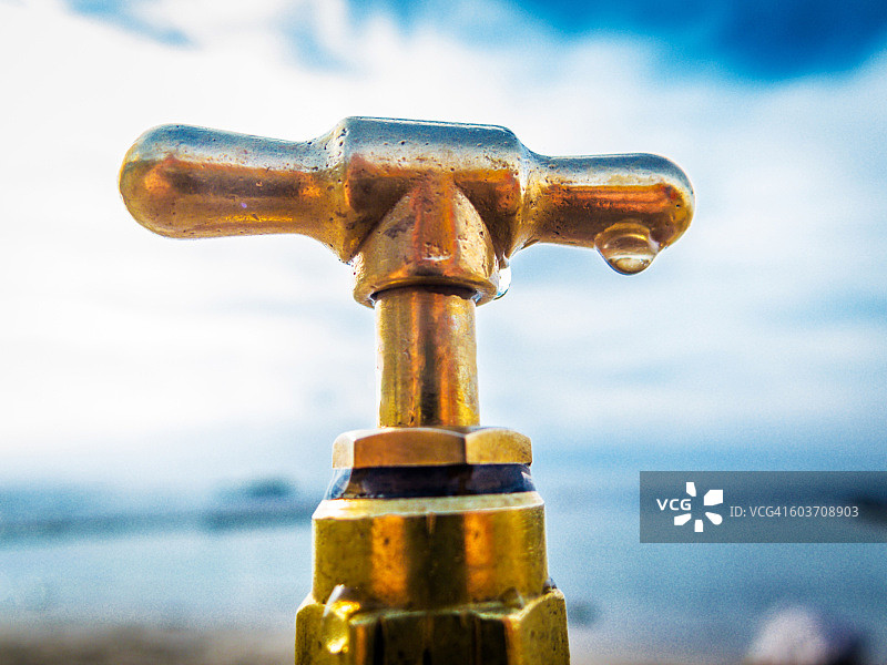 带水滴的黄铜水龙头，南非开普敦圣詹姆斯海滩图片素材