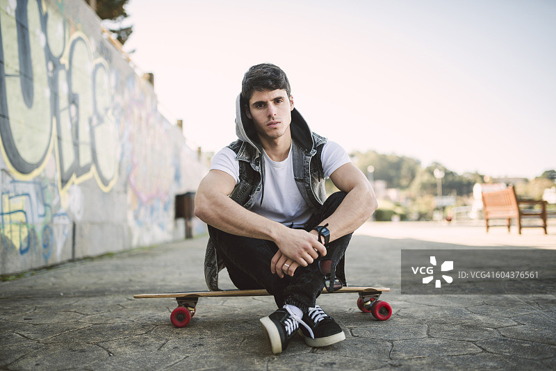 西班牙拉科鲁尼亚：坐在长板上的严肃青年男子肖像图片素材