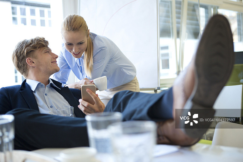 微笑的商人向办公室同事展示手机图片素材