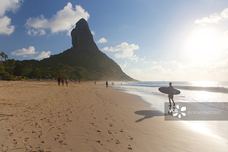 冲浪者漫步在巴西费尔南多·迪诺罗尼亚岛的孔塞桑海滩上图片素材