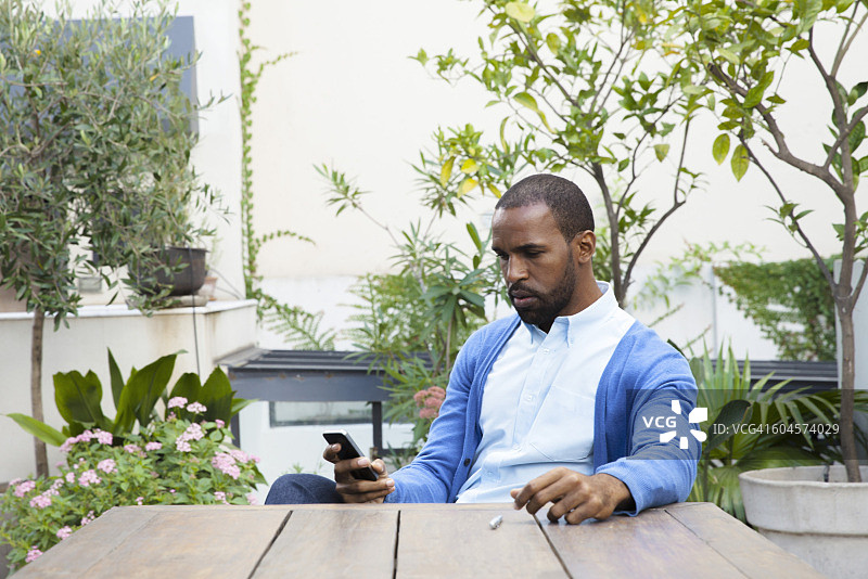 坐在庭院的桌旁打电话的男人图片素材