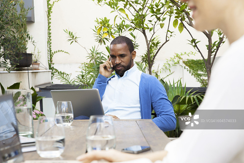 商人户外使用笔记本电脑并拨打电话图片素材