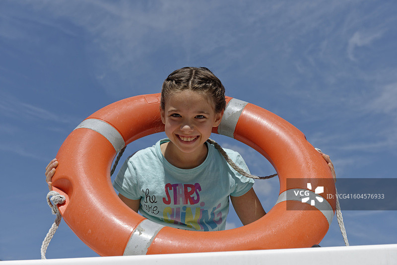 在天空背景下手持救生圈的微笑女孩肖像图片素材