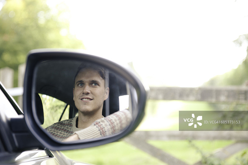后视镜中年轻男子在乡村栅栏旁停车的倒影图片素材