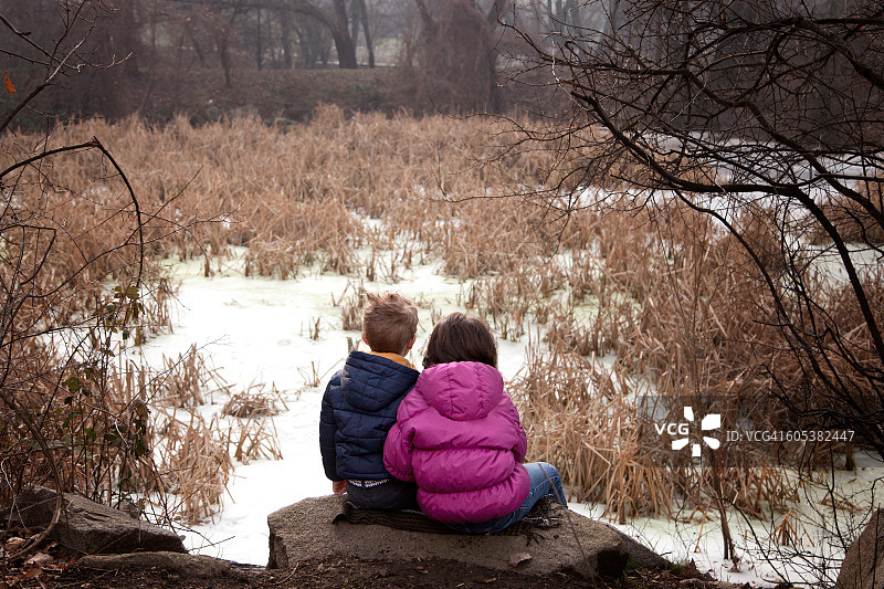 在保加利亚索非亚，坐在森林岩石上的男孩和女孩图片素材