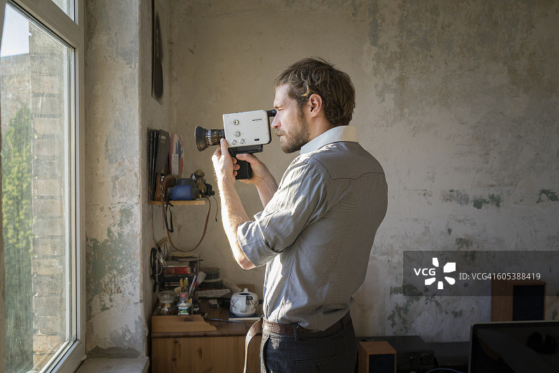 年轻男子用超8毫米电影摄影机拍摄图片素材