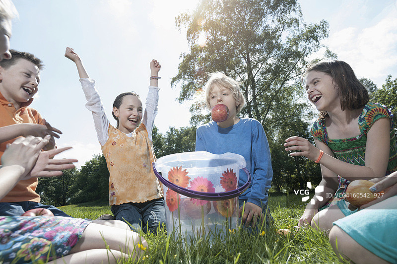 在德国巴伐利亚慕尼黑，男孩试图用嘴从水桶里叼苹果图片素材