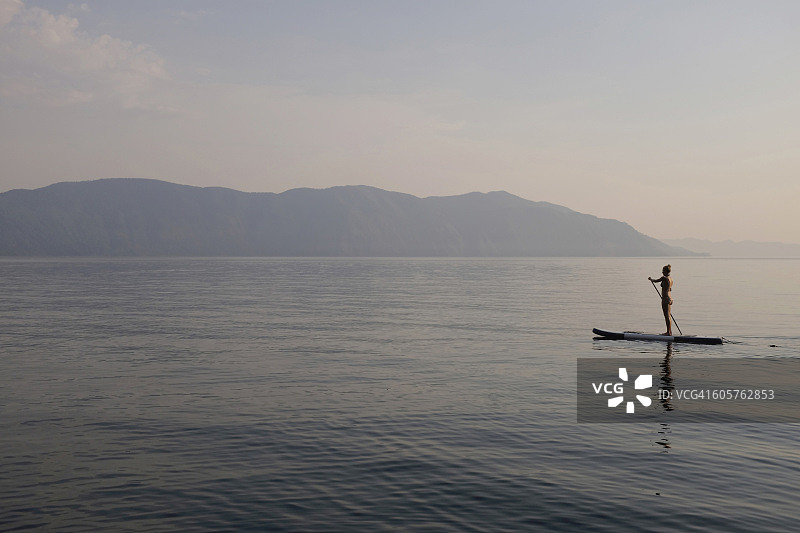 站在湖中桨板上的白人女性图片素材