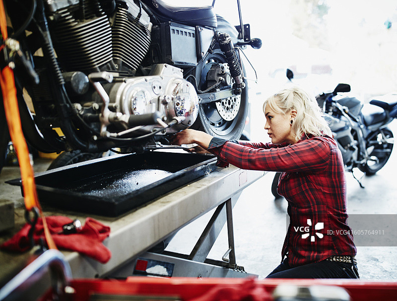 女修理工更换摩托车上的机油图片素材