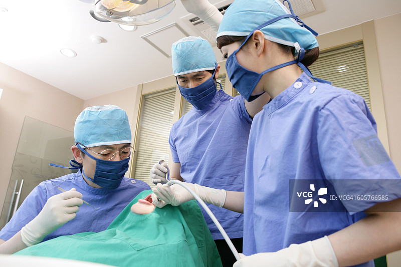 牙医和牙科助手在牙科诊所为病人进行手术图片素材