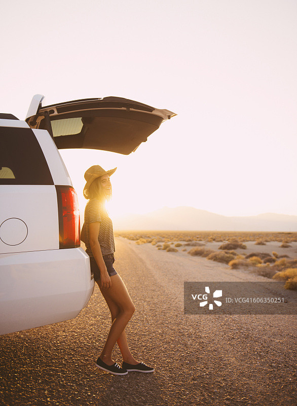 在偏僻的道路上靠在汽车上的西班牙裔女人图片素材